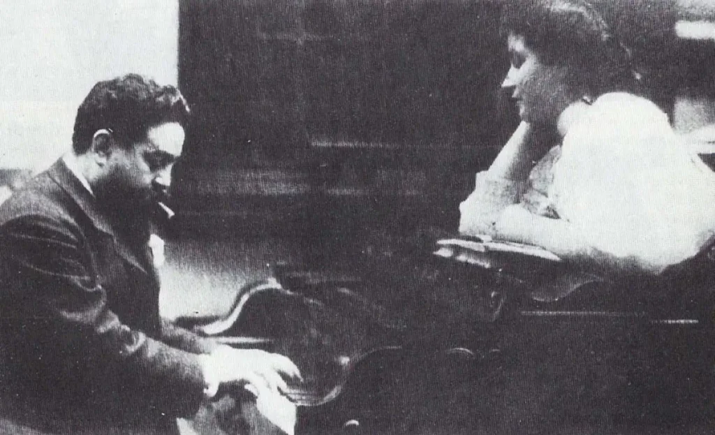 Isaac Albéniz is playing piano while his daughter Laura is looking on